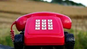 red rotary phone with black wheels near brown grasses during day time