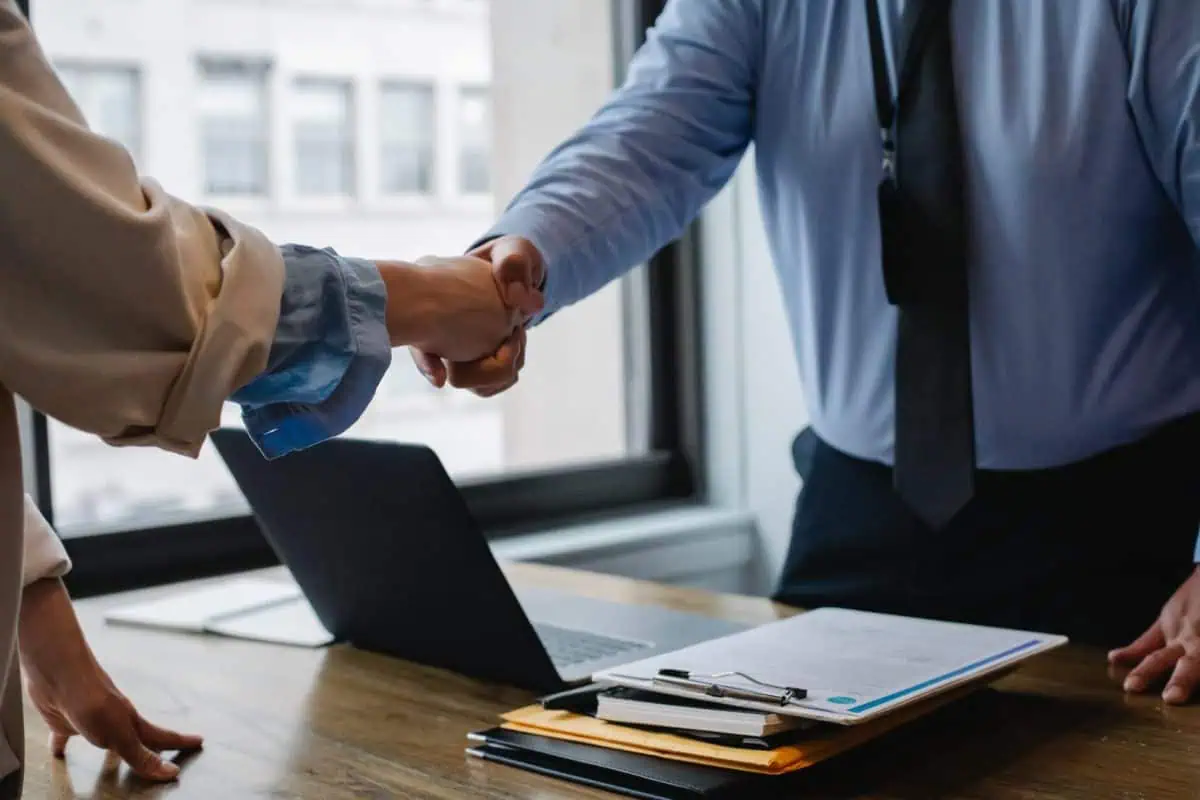 crop colleagues shaking hands in office