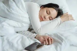 Relaxed woman sleeping peacefully on bed, highlighting mental health, sleep therapy, and wellness services at Davenport Psychology.