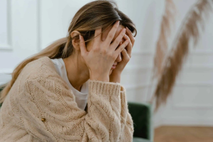 Anxious woman holding her head with hands, experiencing stress or mental health issues in a therapy or counseling setting at Davenport Psychology.