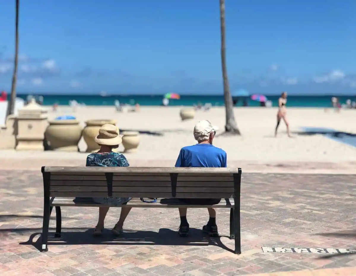 man and woman sitting on brown wooden bench