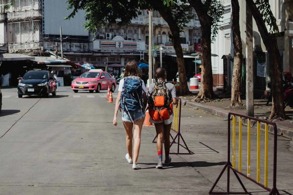 people with backpacks walking city street