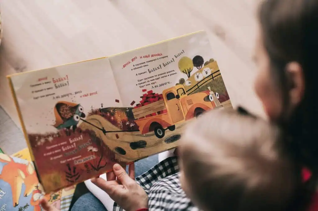 woman reading book to toddler. Parent coaching and support groups can really help with the hard parts of parenting.