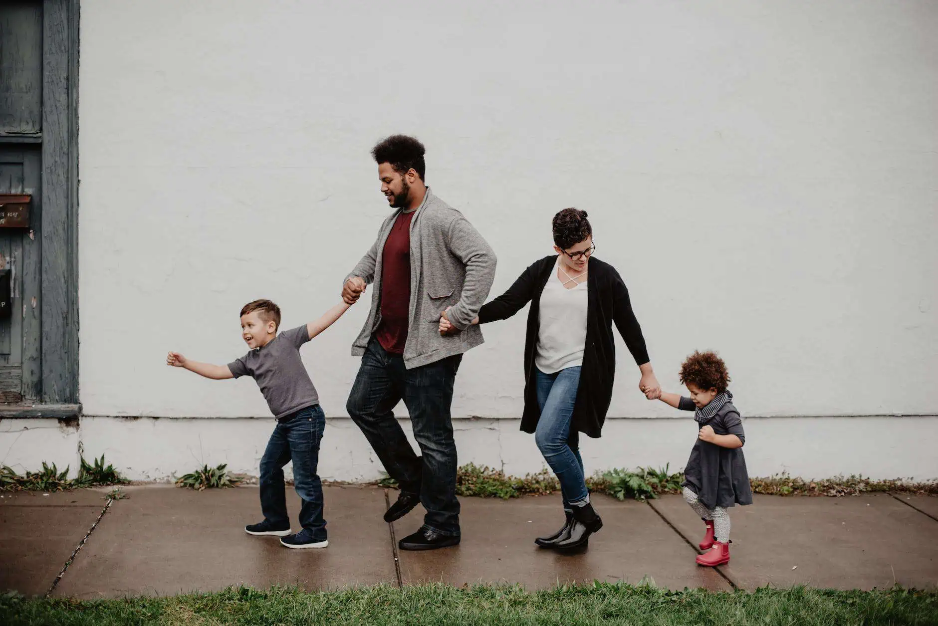 Family of four holding hands, representing connection and healing through family therapy in Sarasota & Venice, FL.