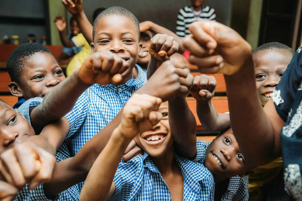 a group of kids holding their fists up and smiling
