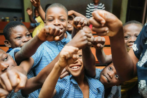 a group of kids holding their fists up and smiling