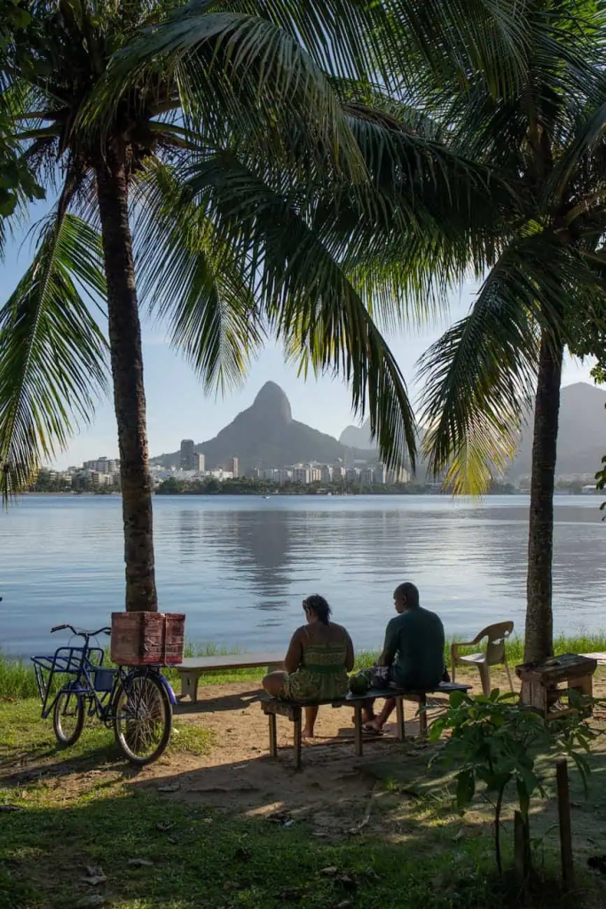 woman and man sitting under palm trees on sea shore