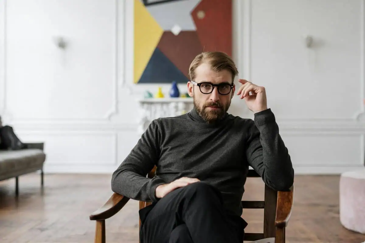 man in black sweater sitting on brown wooden chair