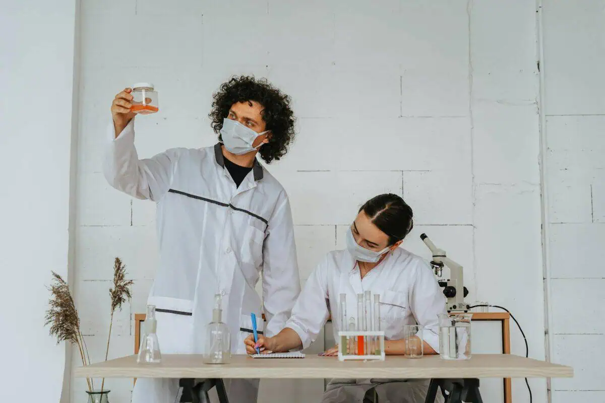 a person wearing face mask holding a jar with red liquid