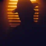 theatric silhouette of head in hat in light detective looking individual.