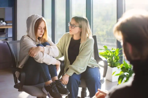 Feeling anxious teen girl comforted by therapist during mental health counseling session at Davenport Psychology, mental health support for teens, therapy for anxiety, adolescent mental health care, professional counseling services.