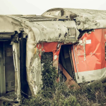 rusty train wreck in overgrown field