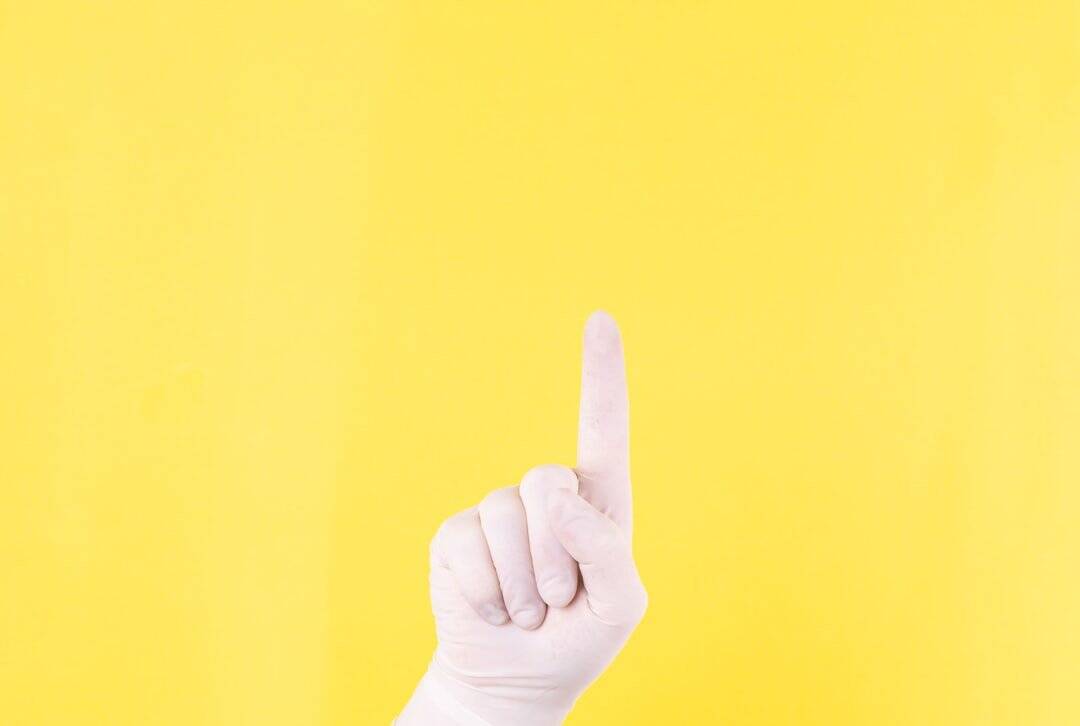 The close plan. Doctor's hand in a white medical glove on a yellow background shows up. The medicine. Place for an inscription. Advertising. Like. Medical gloves.