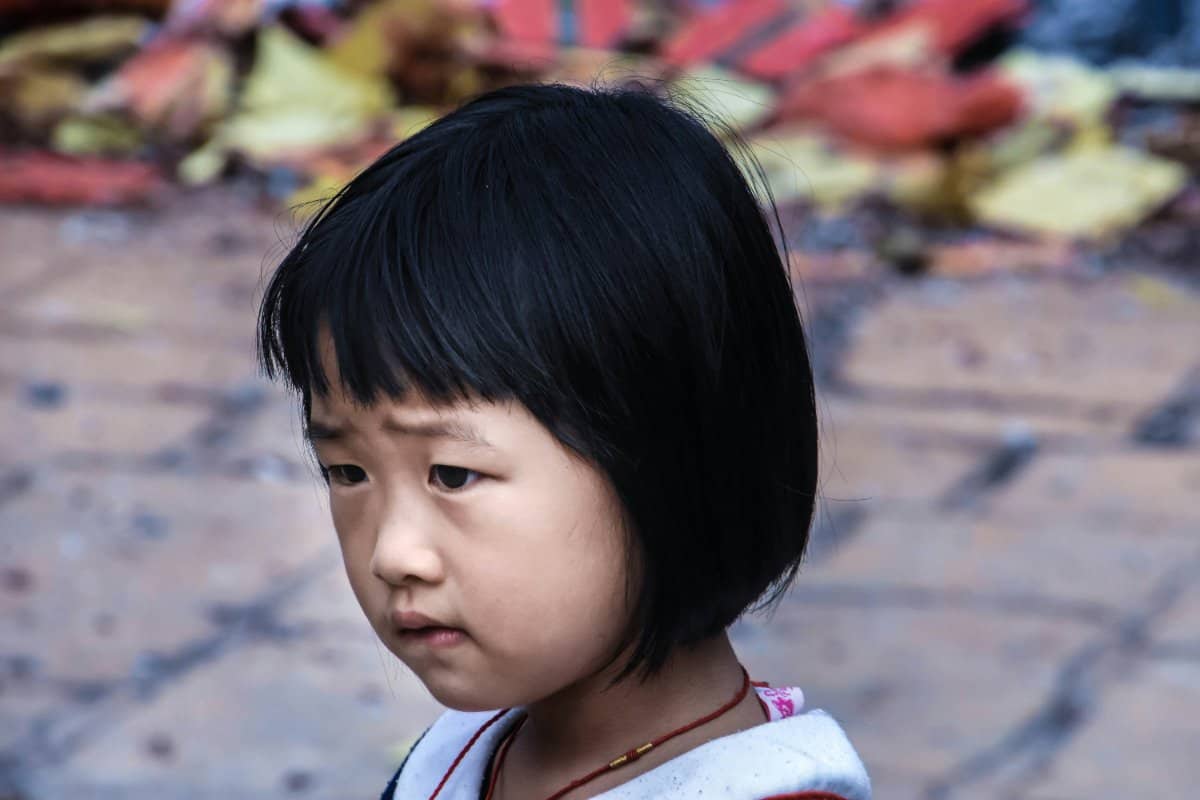 A child holding their head with a thoughtful and stressed expression